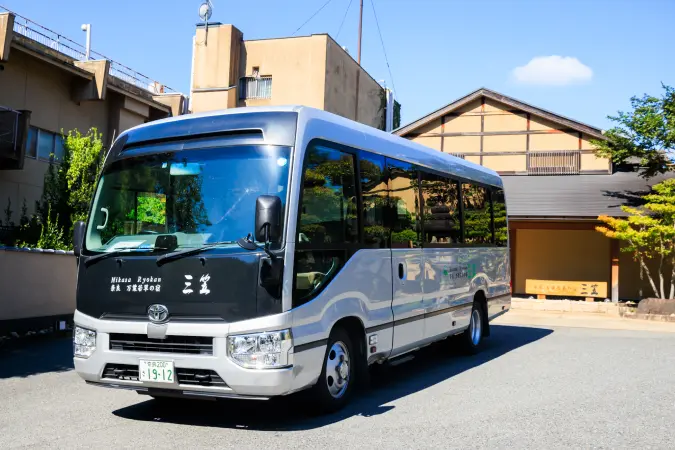 旅館のロゴが入ったシルバーの送迎バス。