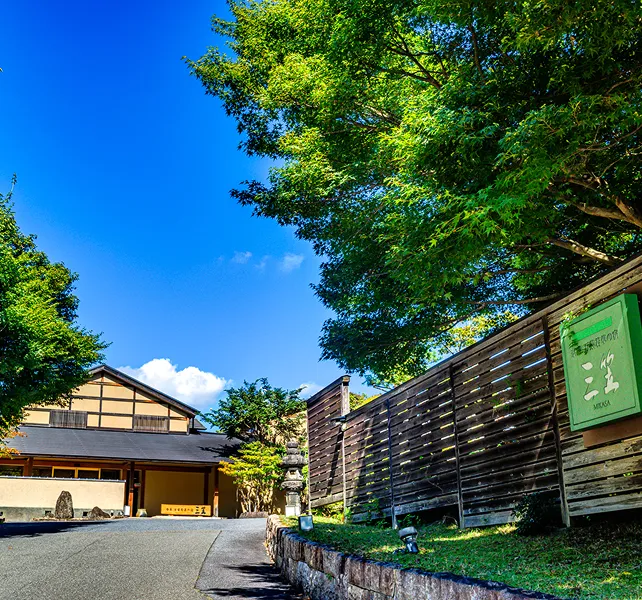 青空のもと、緑に囲まれた旅館の入り口。