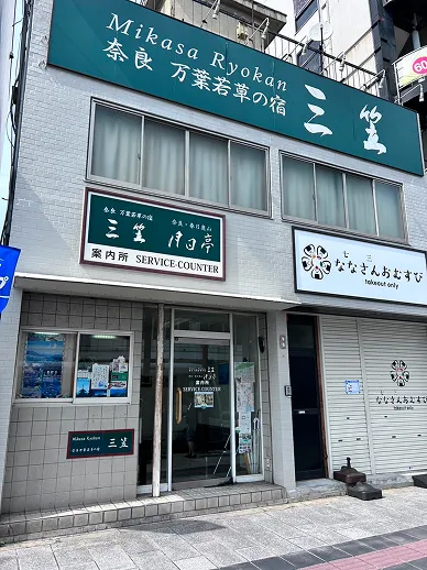 深緑色の奈良万葉若草の宿 三笠と書かれた看板のある案内所の外観