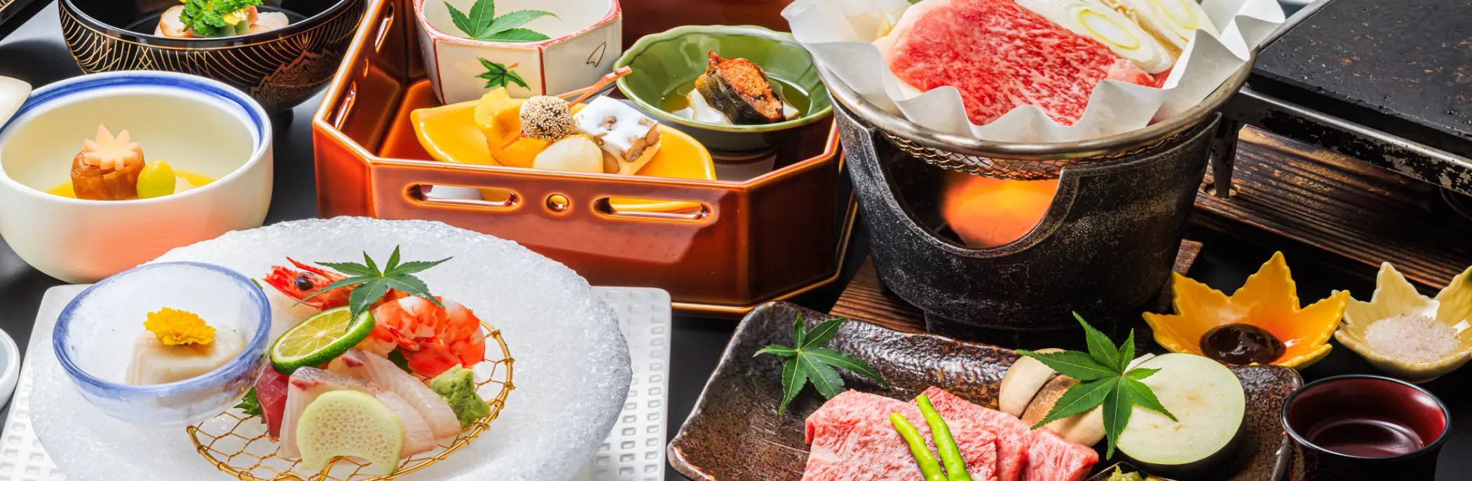 美しい器に盛り付けられた会席料理。刺身や肉料理、小鉢など、色とりどりの料理が並ぶ。