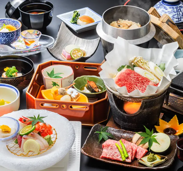 美しい器に盛り付けられた会席料理。刺身や肉料理、小鉢など、色とりどりの料理が並ぶ。