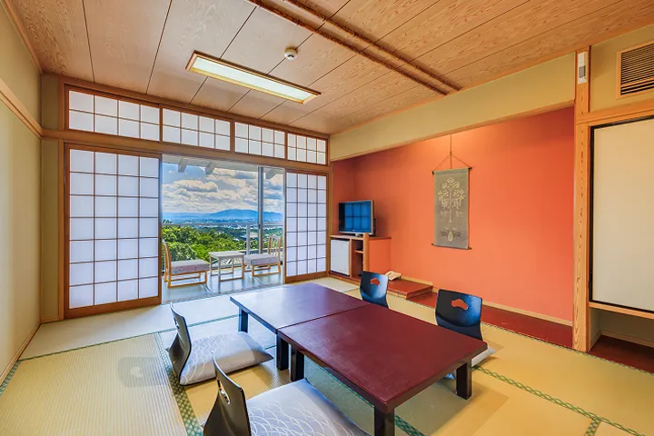 畳の和室。黒いテーブルと座椅子が置かれ、窓からはテラスが見える。