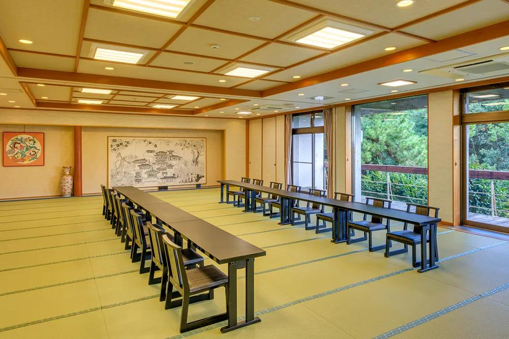 大広間の和室、長机と椅子が整然と並ぶ宴会や会合用の部屋