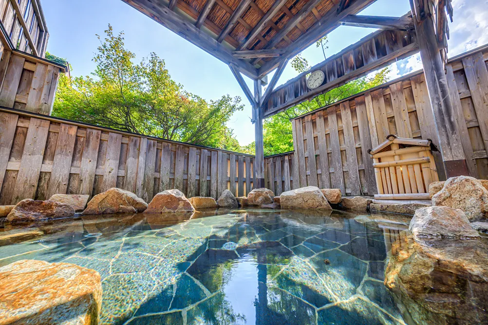 岩に囲まれた露天風呂、透き通った湯が輝いている様子。