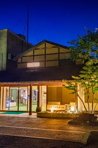 夜の宿泊施設外観、ライトアップされた建物と庭