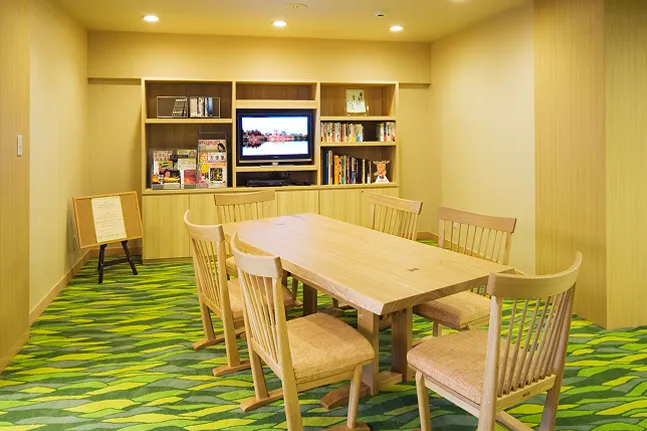 雑誌や本が並んだ棚に、テーブルと椅子が完備されているライブラリー室内