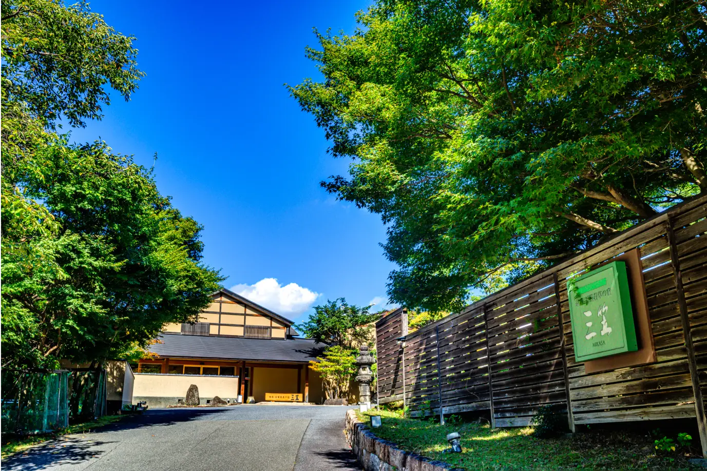 晴れた日に青々とした木々に囲まれた旅館の入り口。