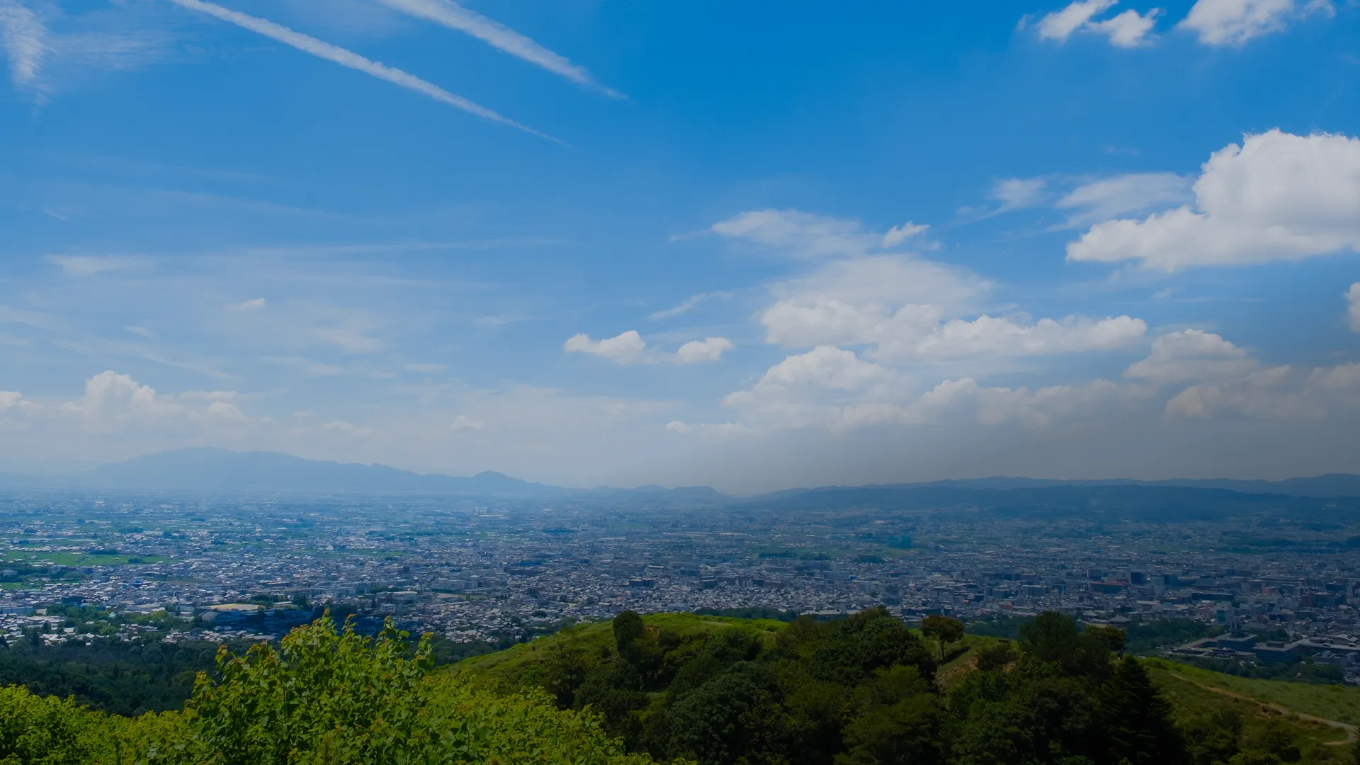 快晴の青空の下、若草山の山頂付近から奈良市街を一望する大パノラマ。