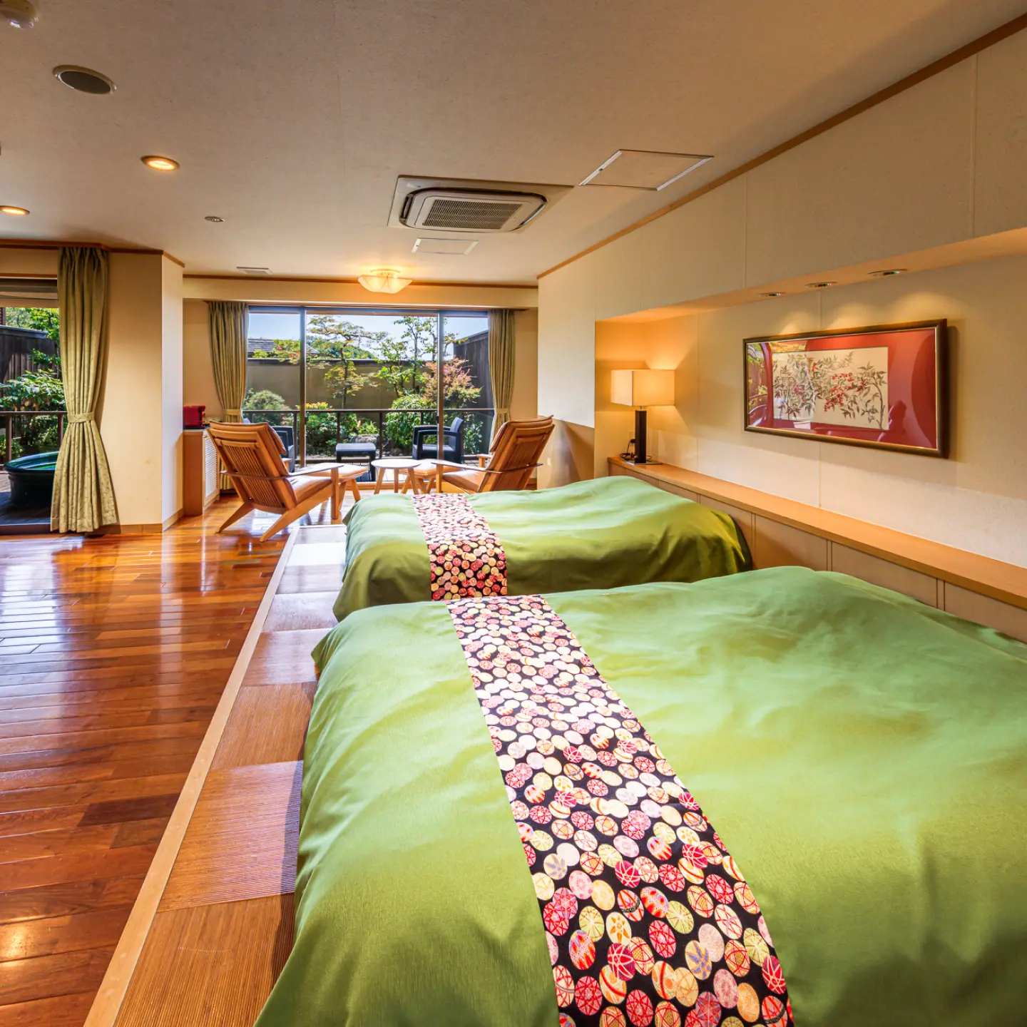 ツインベッドが置かれた和モダンな客室。窓の外には露天風呂付きのテラスが見えます。