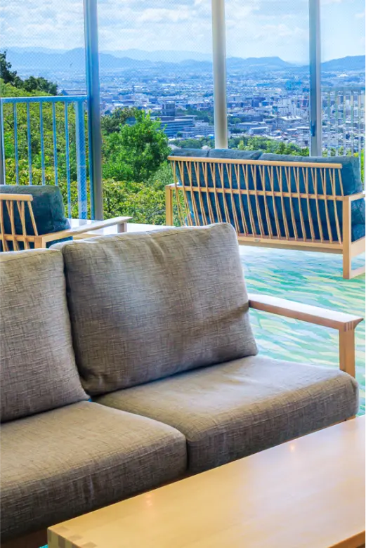 ソファが置かれた窓際のロビー。窓の外には青い空と街並みが広がります。