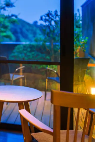 夜のテラス席。テーブルと椅子、そしてライトの明かりが見えます。