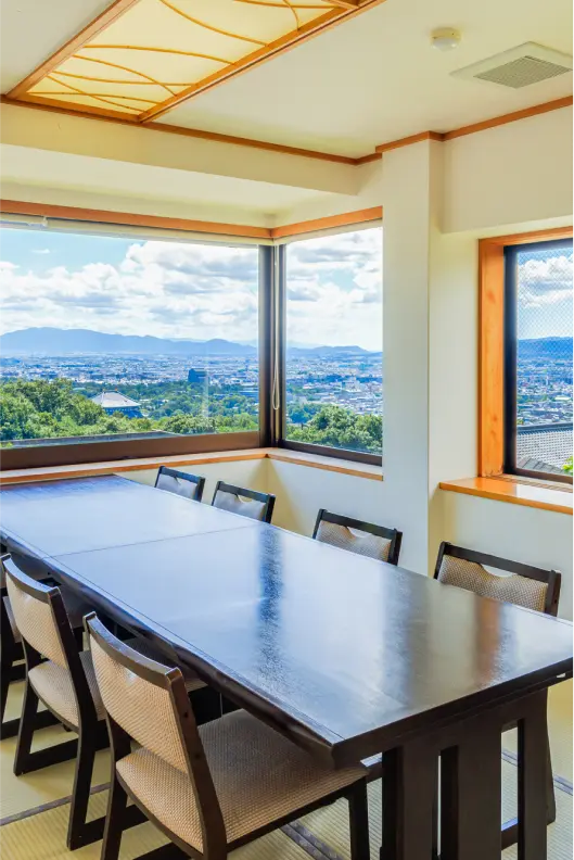 長いテーブルが置かれた畳の部屋。窓の外には広がる街並みが見えます。