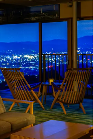 夜景が見える窓際の椅子とテーブル。間接照明が温かみのある雰囲気を醸し出しています。