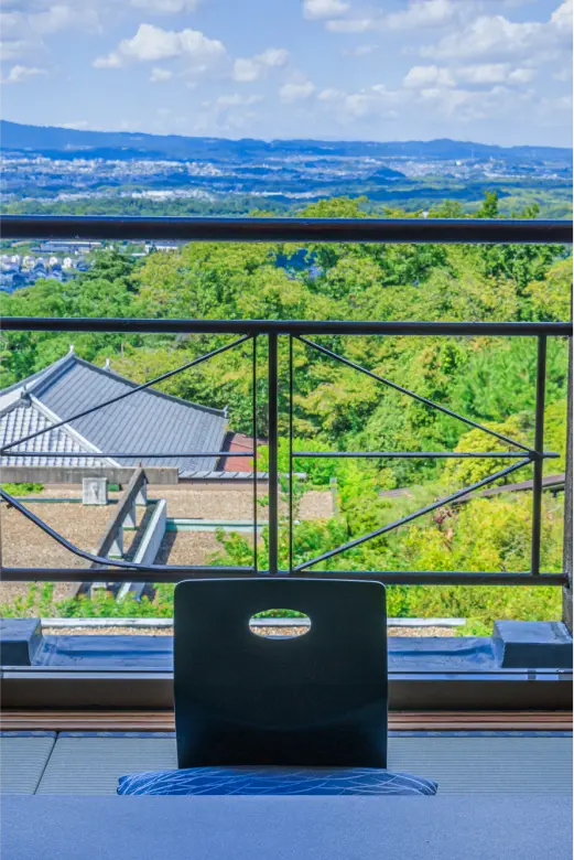 高層階から見える森と街の景色。座布団が置かれた窓際の席。