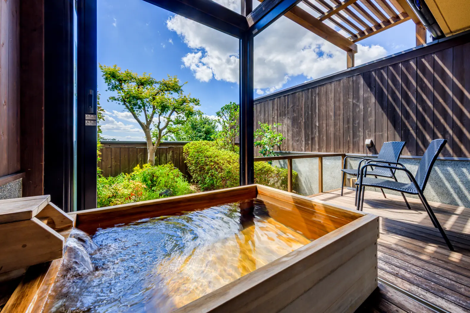 木の浴槽が設置された客室露天風呂と、その奥にチェアが置かれたテラス。