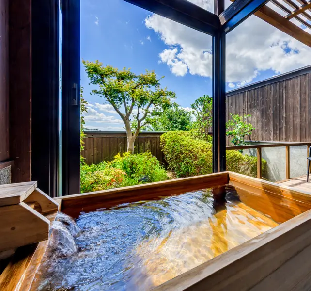 木製の露天風呂（温泉）と庭園が見えるデッキ
