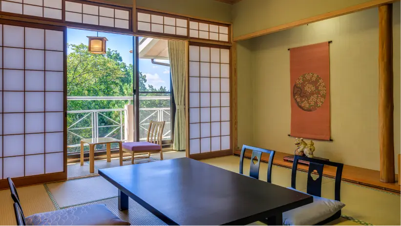 木々の景色が見えるバルコニー付きの伝統的な和室（畳の部屋）。