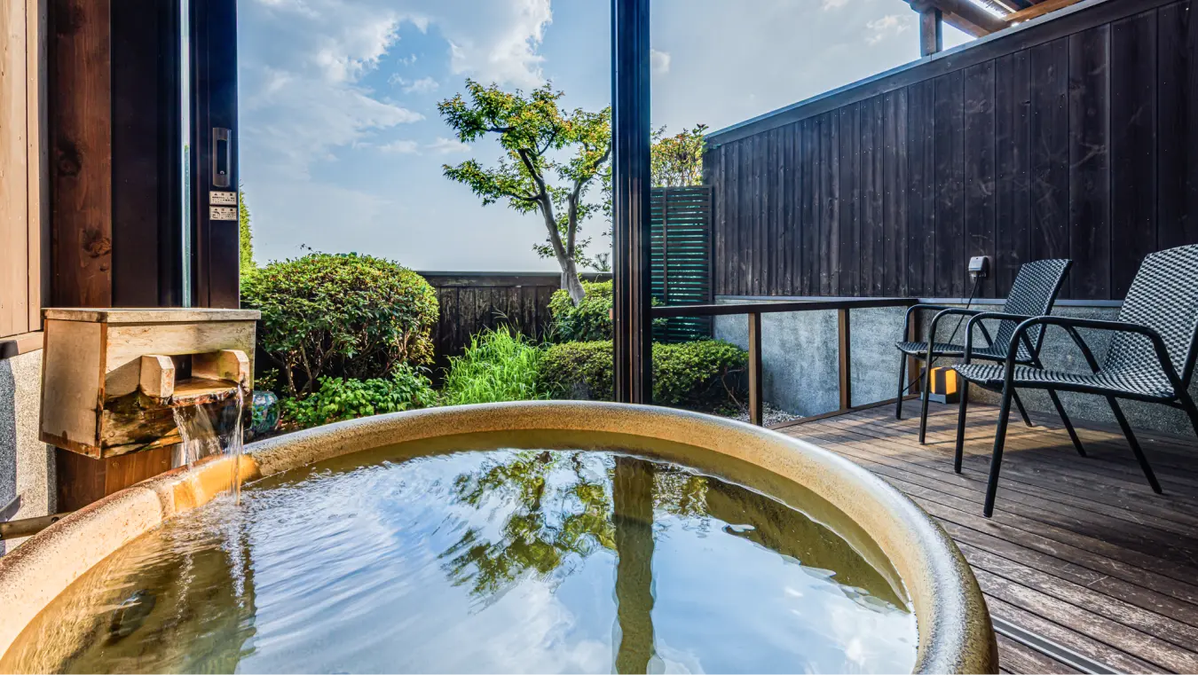丸い形をした露天風呂（温泉）と庭が見えるデッキ。