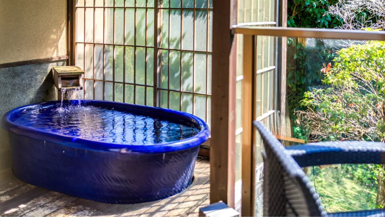 プライベートな木製デッキにある深い青色の露天風呂（温泉）。