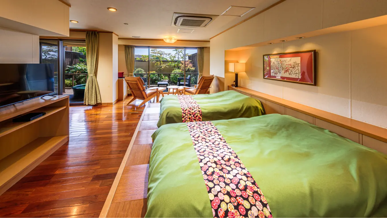フローリングとベッドがある和モダンな客室。窓の外に庭が見える。