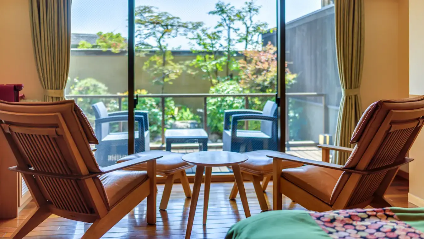庭と屋外椅子が見える窓際の革製のアームチェアとテーブル。