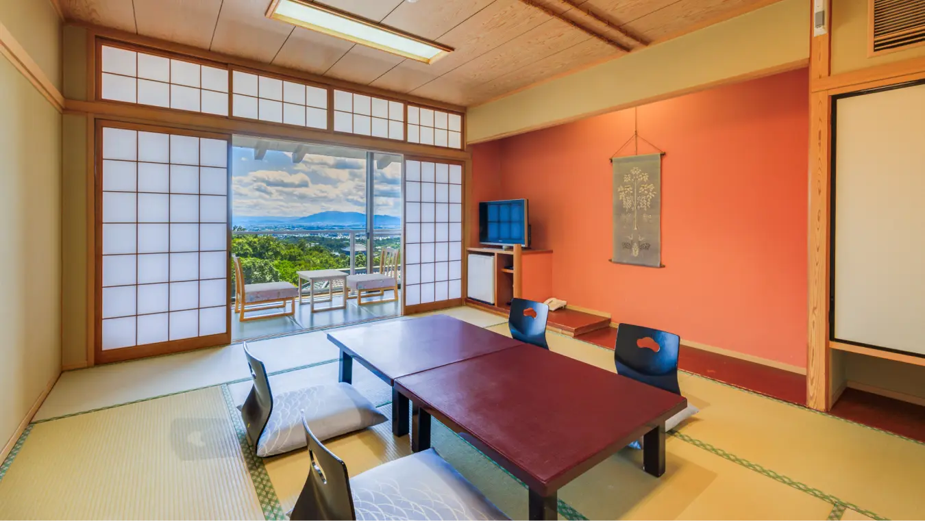 遠くに山と街並みが見える展望付きの和室。