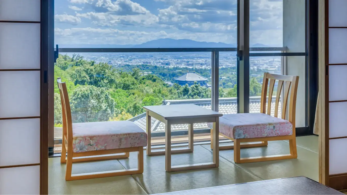 街並みと山々が見える展望付きの窓際の椅子とテーブル。