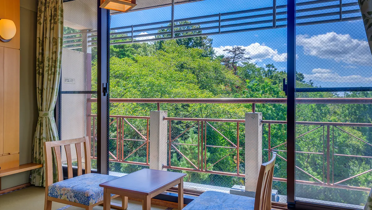 窓辺の椅子とテーブルから緑豊かな景色を望む