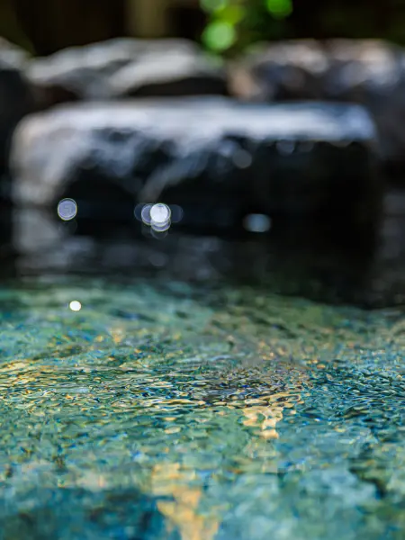 岩風呂の水面をクローズアップした写真。水面が光を反射して輝いています。