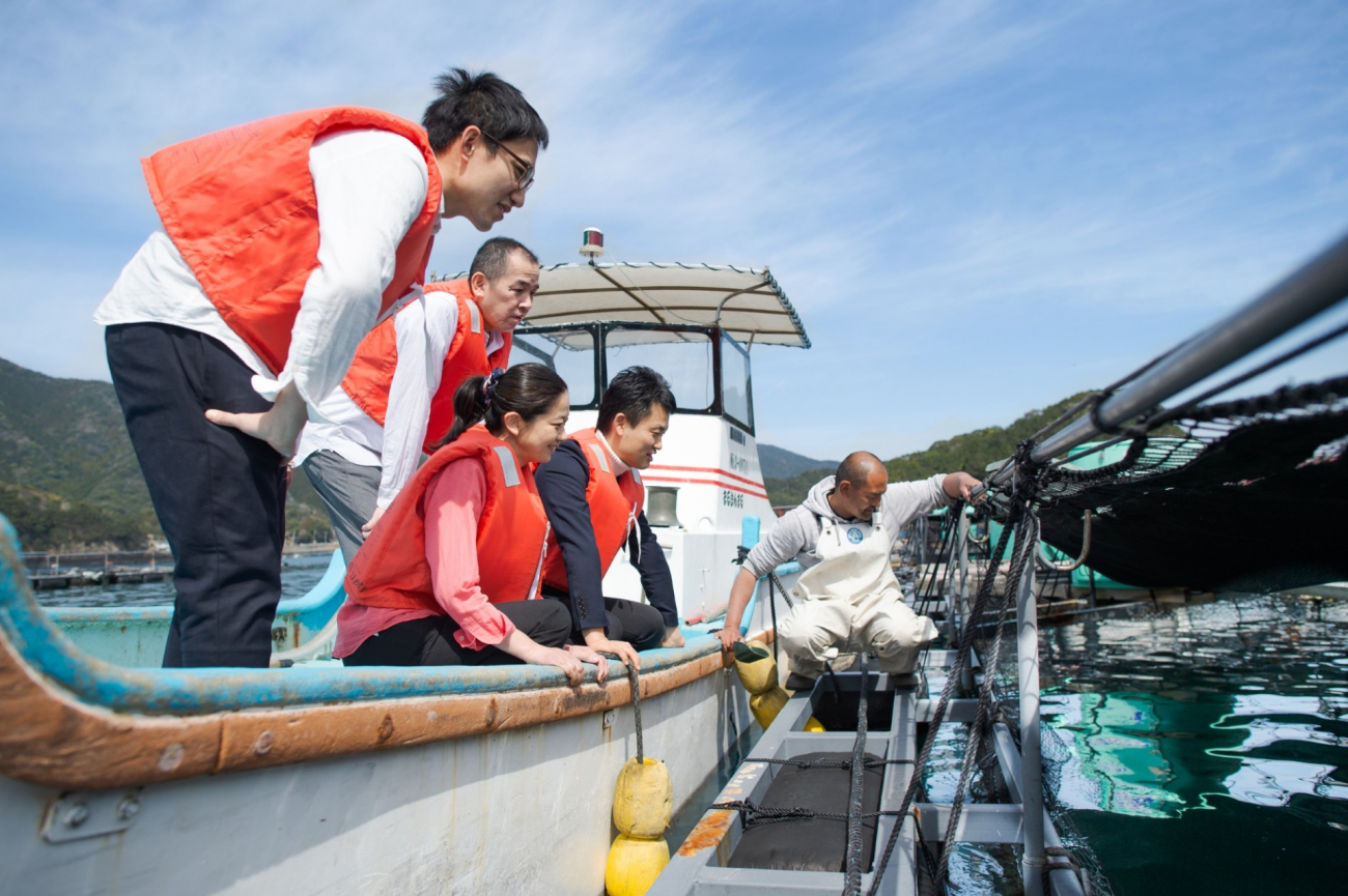漁船から真鯛の養殖筏を見学する村瀬さん（左）と浅川さん（右）